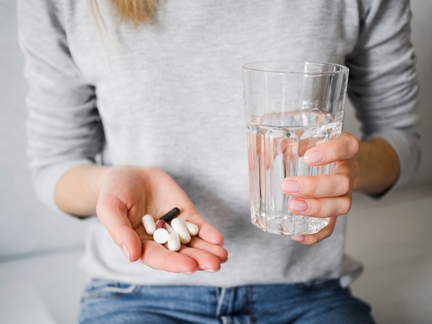 Mujer sosteniendo pastillas y vaso de agua