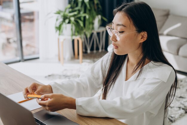 Mujer sosteniendo pegatinas para tomar notas en el libro mientras estudia