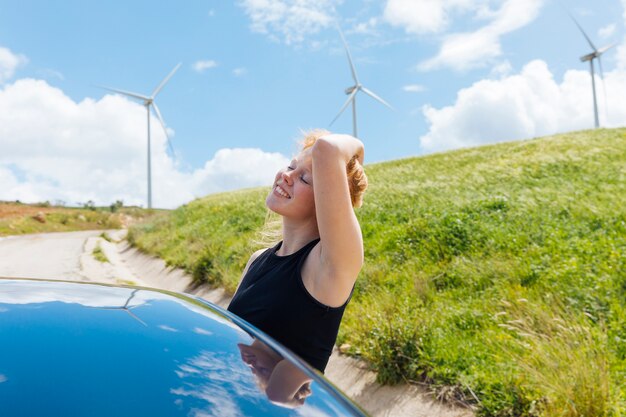 Mujer sosteniendo el pelo y disfrutando del sol por la ventana del coche