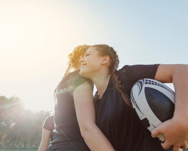 Mujer sosteniendo una pelota y abrazando a su compañero de equipo