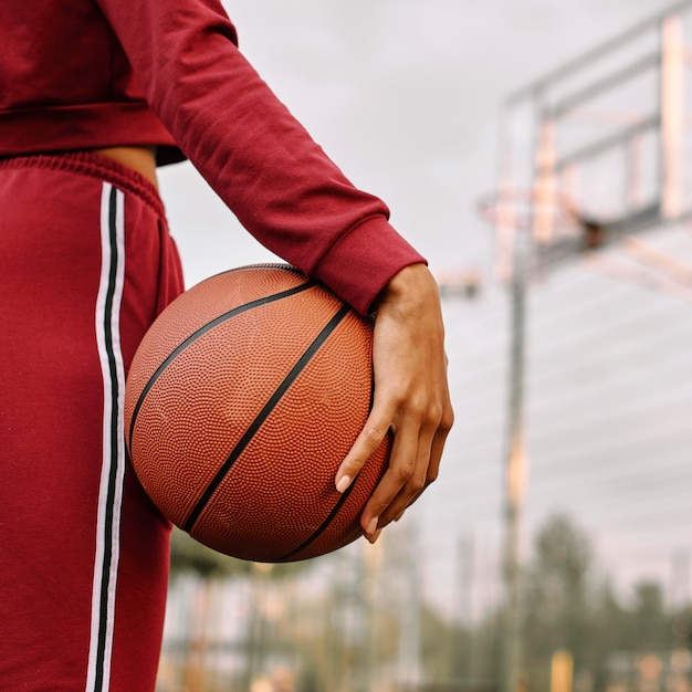 Mujer sosteniendo una pelota de baloncesto junto a sus piernas