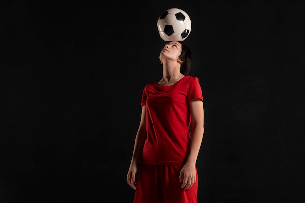 Mujer sosteniendo una pelota de fútbol en la cabeza.