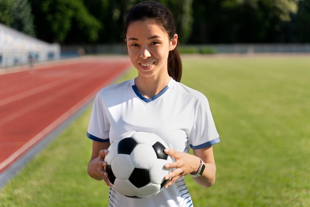 Mujer sosteniendo una pelota de fútbol en el campo