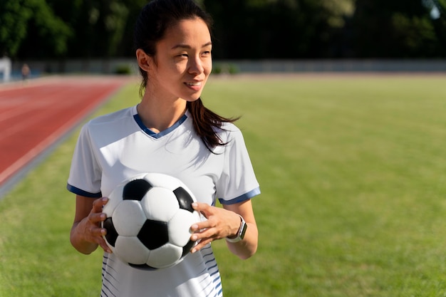 Mujer sosteniendo una pelota de fútbol en el campo