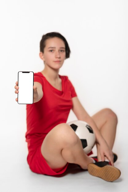 Foto gratuita mujer sosteniendo una pelota de fútbol y teléfono