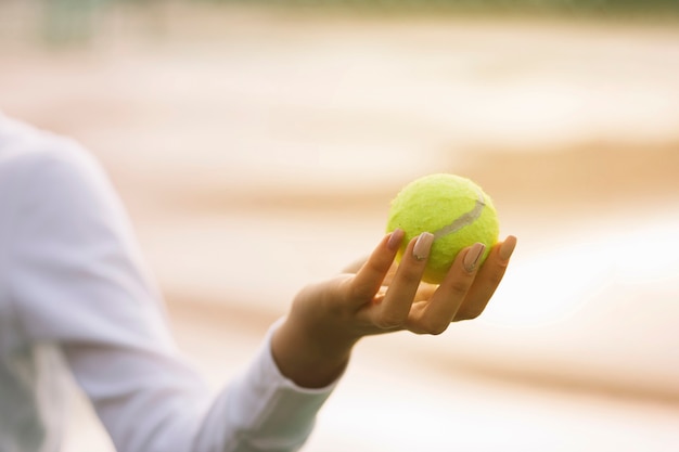 Mujer sosteniendo una pelota de tenis en una mano