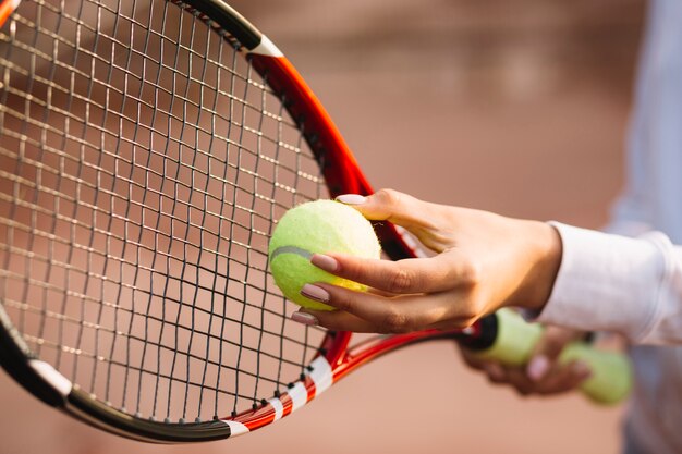 Mujer sosteniendo una pelota de tenis y raqueta