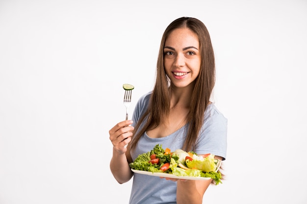 Mujer sosteniendo un pepino y ensalada