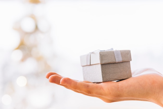 Mujer sosteniendo pequeña caja de regalo gris en la mano