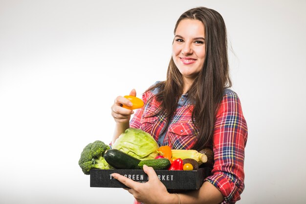 Mujer sosteniendo pimienta y paleta con verduras