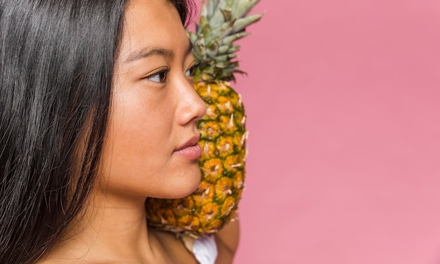 Mujer sosteniendo una piña en primer plano de su hombro