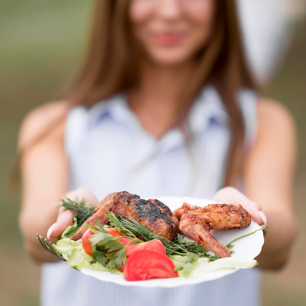 Mujer sosteniendo placa con barbacoa al aire libre