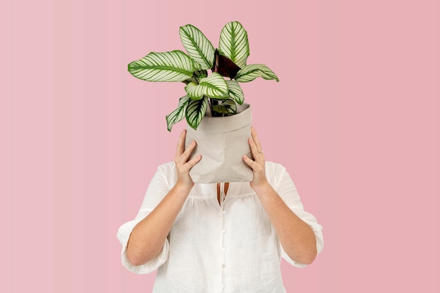 Mujer sosteniendo planta en maceta en envases sostenibles