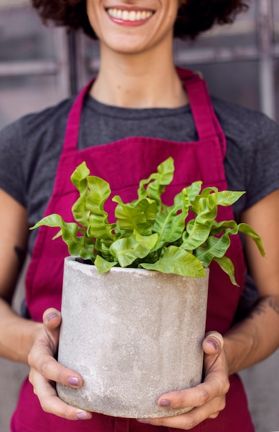 Foto gratuita mujer sosteniendo una planta en un primer plano de maceta blanca