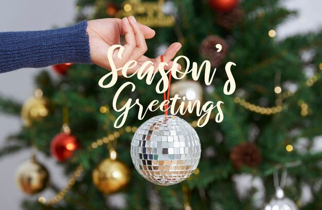 Mujer sosteniendo plata bola de discoteca de Navidad en la parte posterior del árbol de Navidad