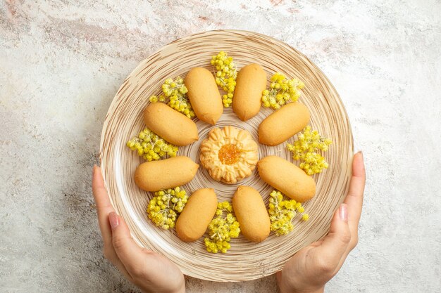 Mujer sosteniendo un plato de deliciosas galletas dulces sobre un fondo de mármol blanco