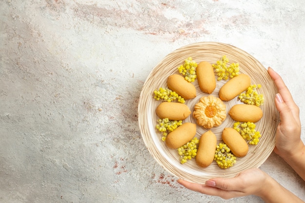 Mujer sosteniendo un plato de galletas variadas del lado derecho del suelo de mármol