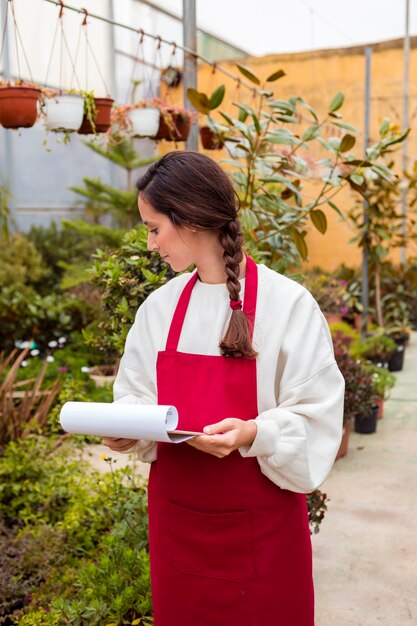 Mujer sosteniendo portapapeles comprobando flores