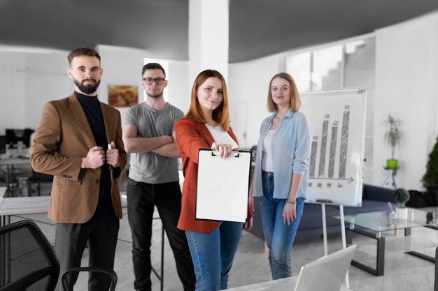 Mujer sosteniendo un portapapeles junto a sus compañeros de trabajo