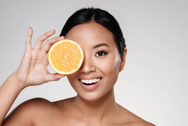 mujer sosteniendo rodajas de naranja cerca de su cara