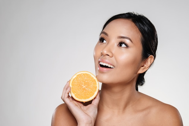 Foto gratuita mujer sosteniendo rodajas de naranja cerca de su cara