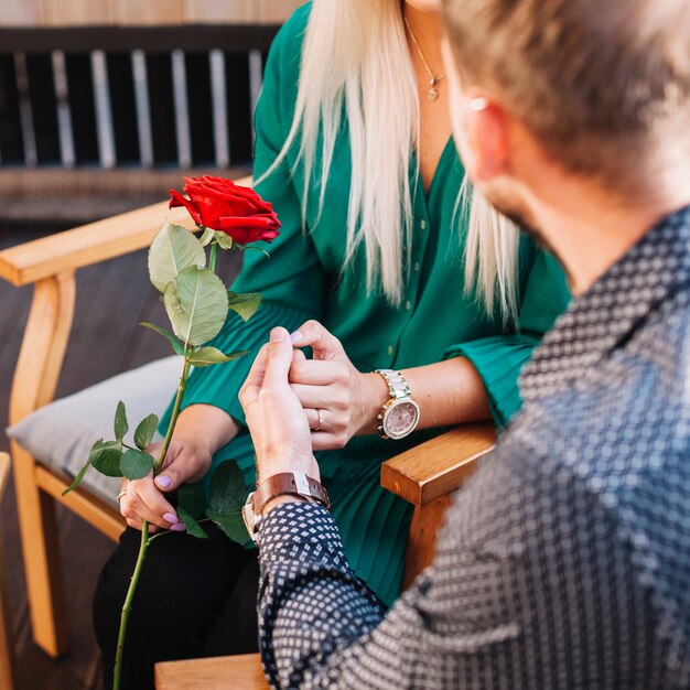 Mujer sosteniendo rosa roja con la mano de su novio