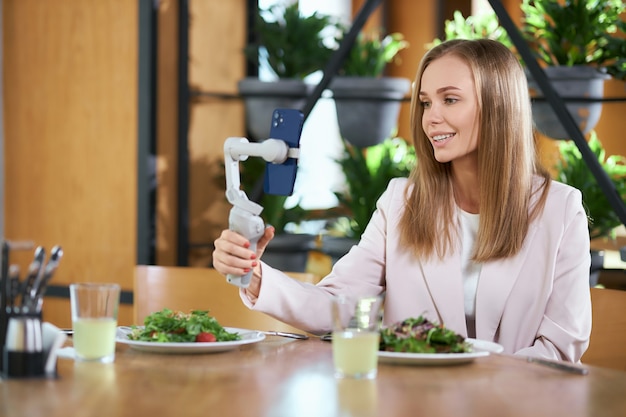 Mujer sosteniendo selfie stick con teléfono y haciendo selfie