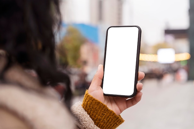 Mujer sosteniendo un smartphone en blanco fuera