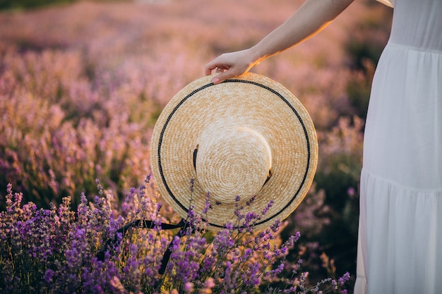 Mujer sosteniendo sombrero en un campo de lavanda cerrar