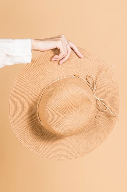 Foto gratuita mujer sosteniendo un sombrero de playa de ala ancha