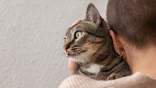 Mujer sosteniendo su adorable gatito en el interior