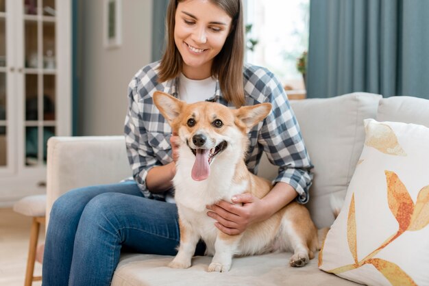 Mujer sosteniendo a su adorable perro en el sofá
