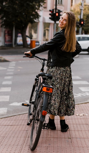 Foto gratuita mujer sosteniendo su bicicleta desde atrás shot