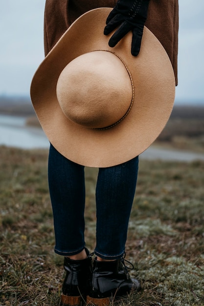 Foto gratuita mujer sosteniendo su sombrero mientras está al aire libre