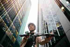 Foto gratuita mujer sosteniendo su teléfono inteligente y caminando en su bicicleta