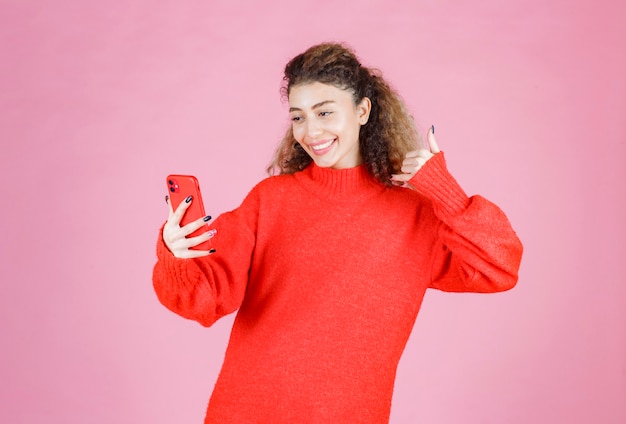 mujer sosteniendo su teléfono inteligente y tomando su selfie.
