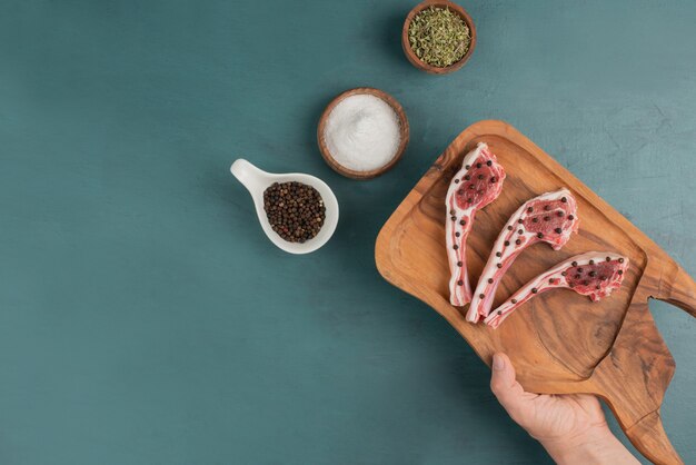 Mujer sosteniendo tablero de madera de trozos de carne cruda.