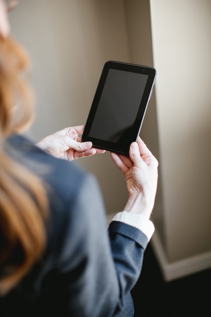 Mujer sosteniendo tablet o smartphone con manos, pantalla negra