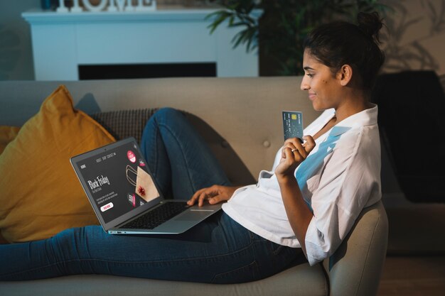 Mujer sosteniendo una tarjeta y trabajando en la computadora portátil