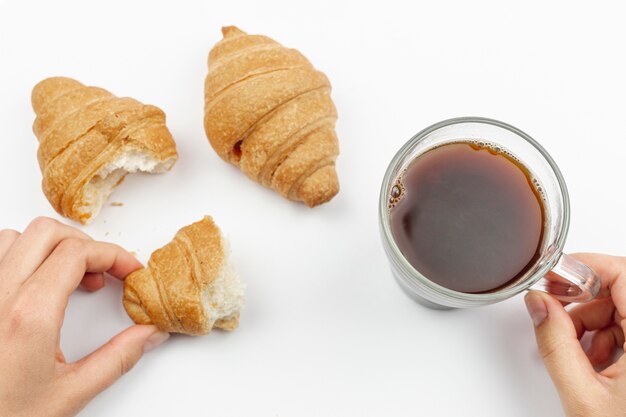 Mujer sosteniendo una taza de café y croissant