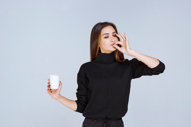 mujer sosteniendo una taza de café y disfrutando del sabor.