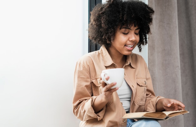 Foto gratuita mujer sosteniendo una taza de café y leyendo