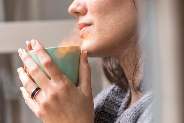 Mujer sosteniendo una taza de café mientras mira afuera
