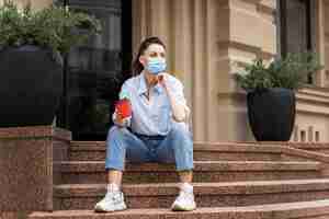 Foto gratuita mujer sosteniendo una taza de café mientras está sentado en las escaleras con espacio de copia