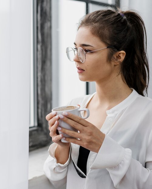 Mujer sosteniendo una taza de café mientras trabaja desde casa
