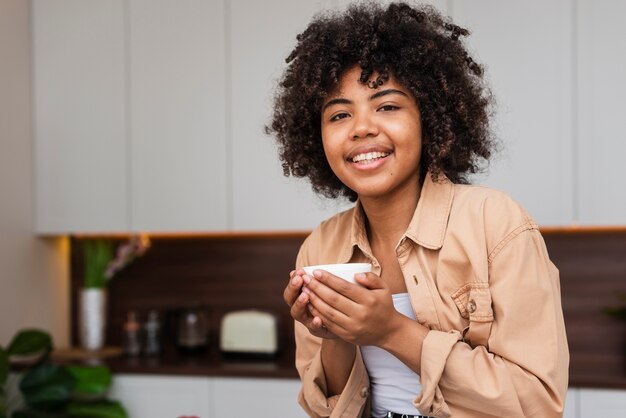 Mujer sosteniendo una taza de café y mirando al fotógrafo