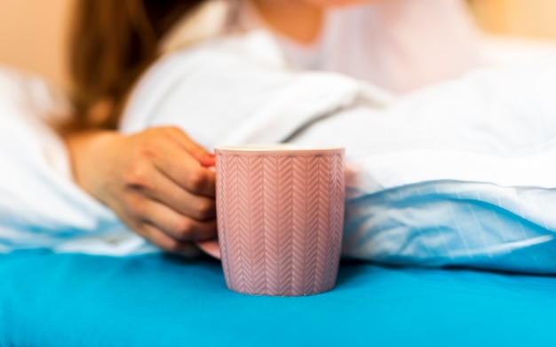 Foto gratuita mujer sosteniendo la taza mientras está acostado en la cama