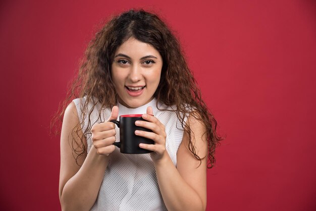 Mujer sosteniendo taza oscura caliente en rojo