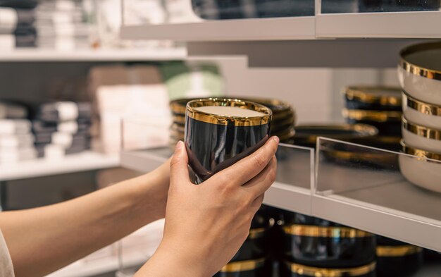 Mujer sosteniendo una taza en la tienda el concepto de elegir platos