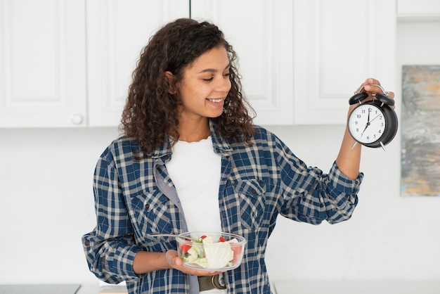 Foto gratuita mujer sosteniendo un tazón una ensalada y un reloj